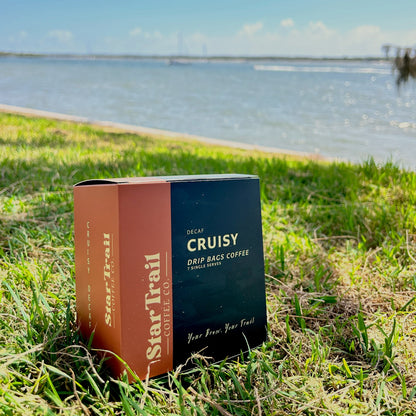 Star Trail Coffee Co. decaf coffee bags on grass with a lake in the background